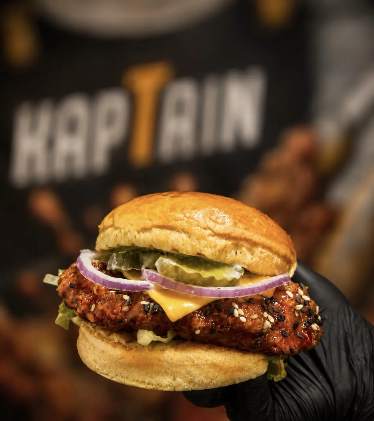 Burger Korean tenu devant l'enseigne Kaptain